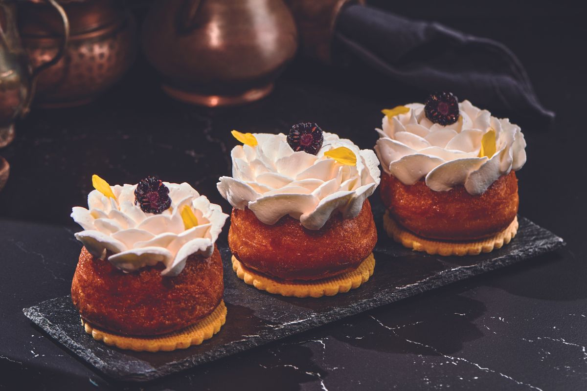 Savarin analcolico con panna e more. Dolci monoporzione su piatto nero. Ricetta savarin senza alcol.