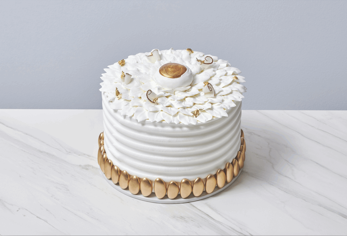 Torta esotica al cocco. Elegante torta bianca con decorazioni dorate.