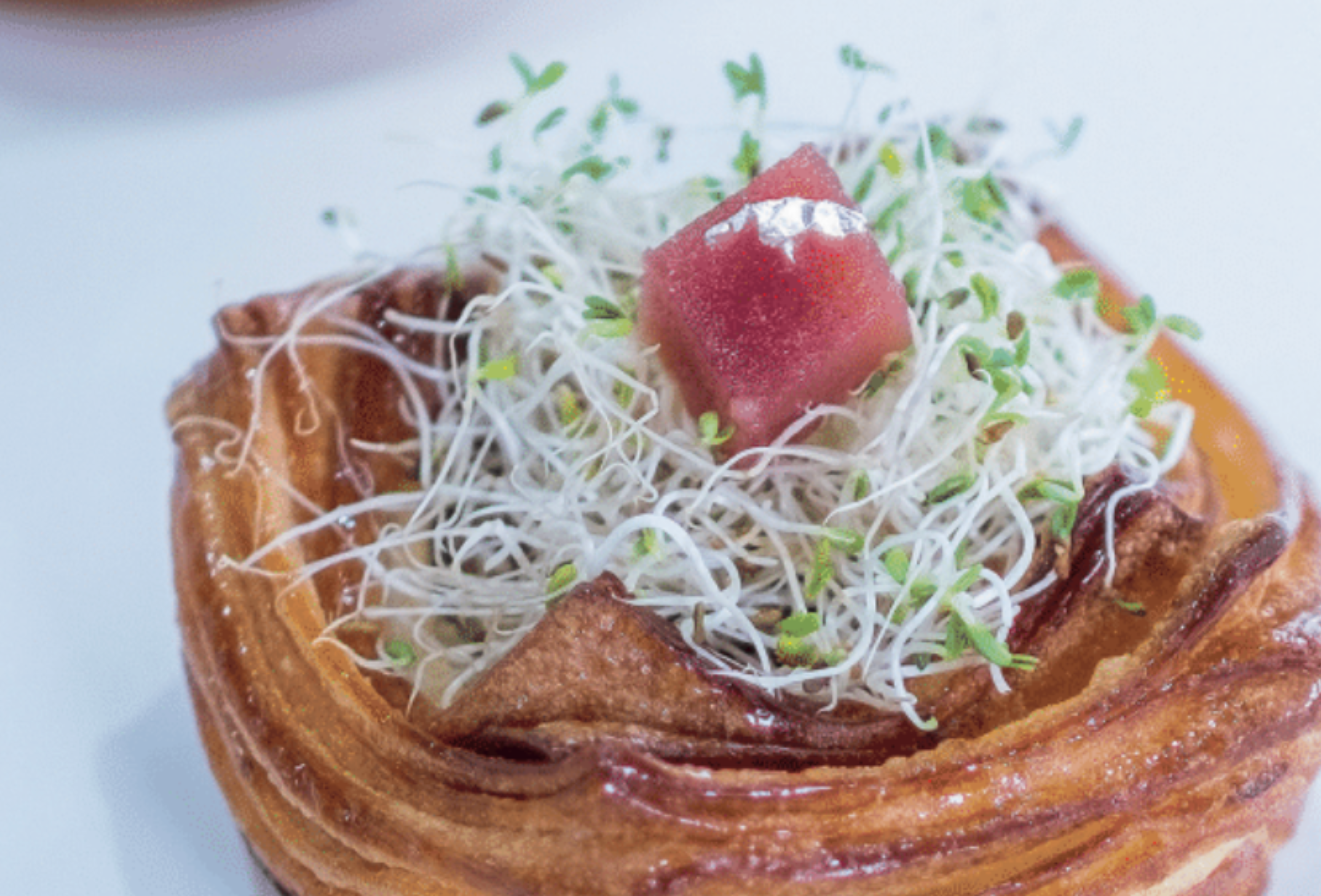 Sfogliato ripieno al formaggio Nido Astur. Pasticceria gourmet con germogli e decorazione.